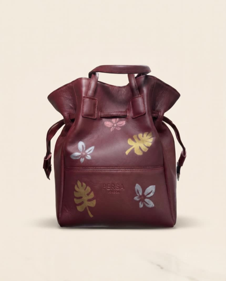 Hand-painted Persian leaf motif on a burgundy leather bucket bag